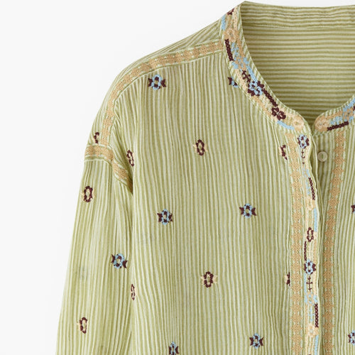 Green embroidered shirt with floral patterns on a white background