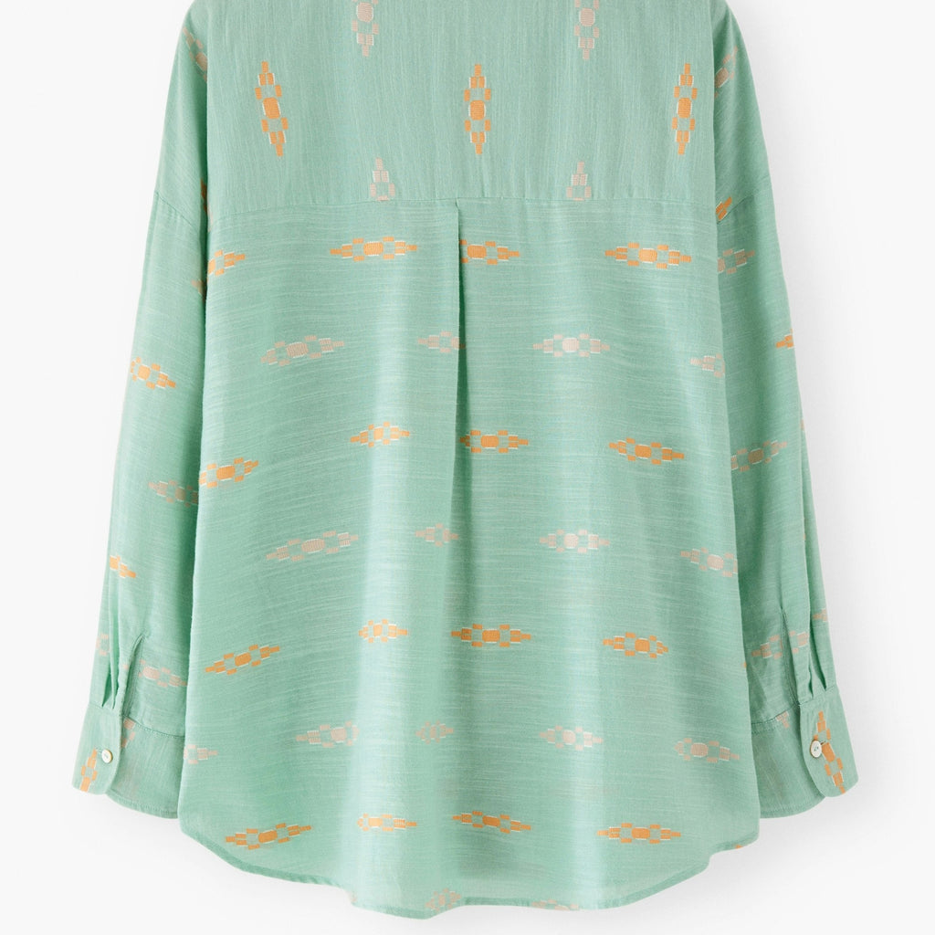 Green blouse with gold patterns on a white background
