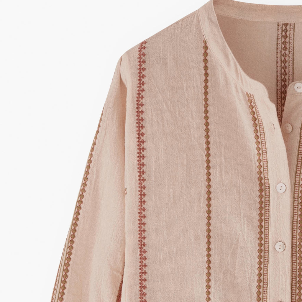 Beige shirt with intricate embroidery on a white background