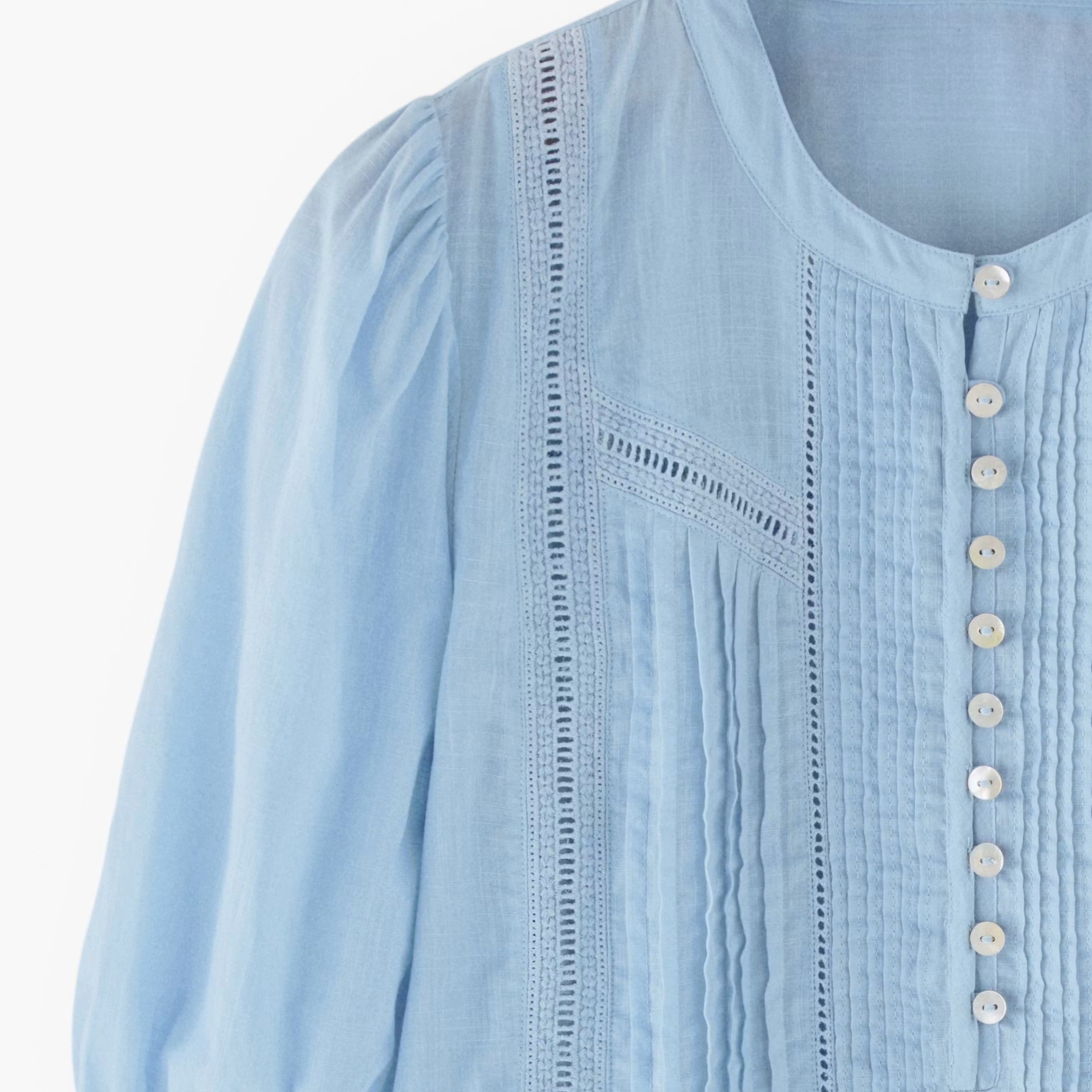 Light blue blouse with button details on a white background